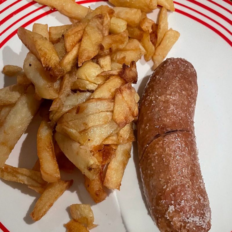 The chips on a plate with a monstrous sausage